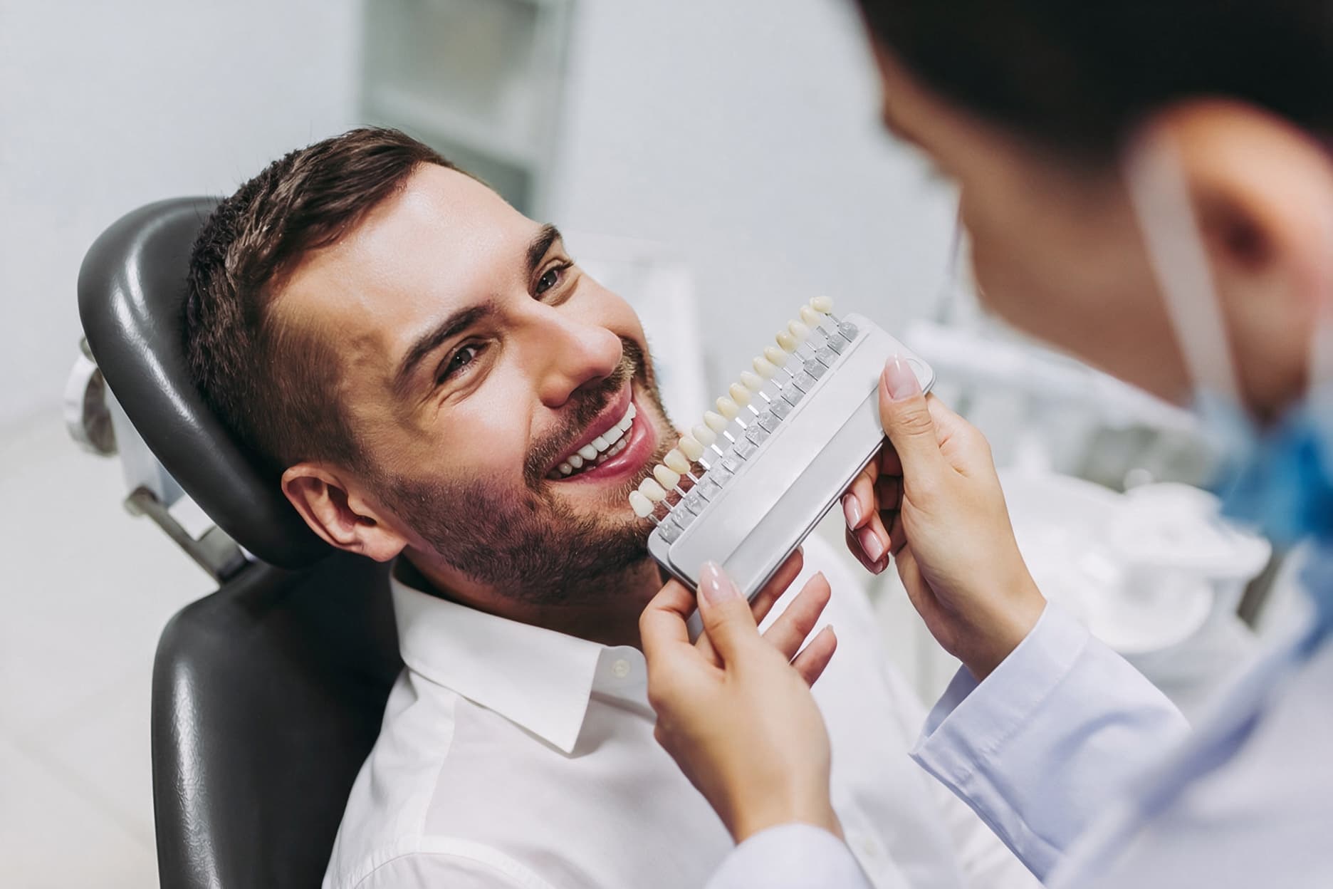 Smiling patient having his veneer shade matched with a shade guide