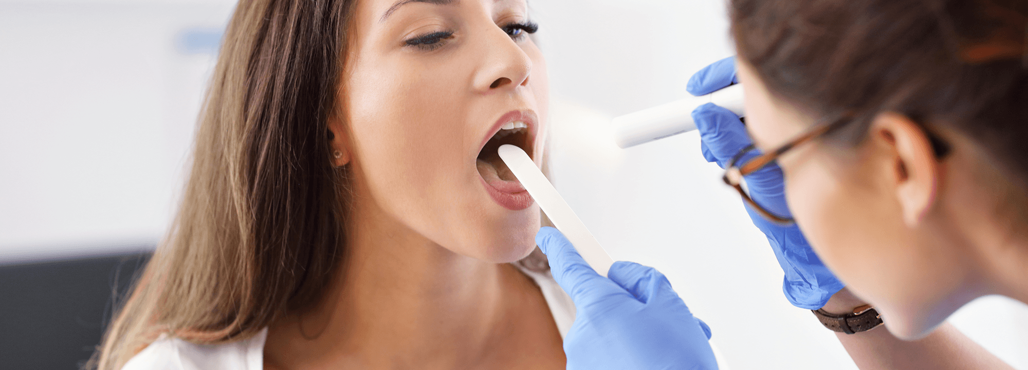 Patient's mouth and throat being examined with a light during an oral cancer screening