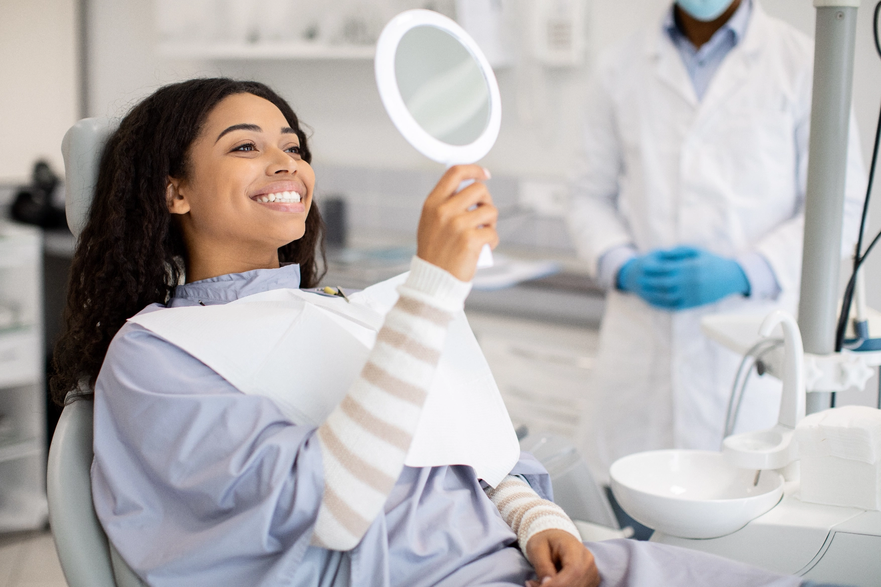 Smiling dental patient admiring her teeth in a hand mirror